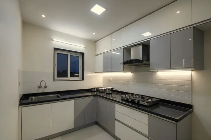 Modular kitchen with a ceiling LED panel, a batten tube light and an LED strip under the wall cabinets lighting the granite counter